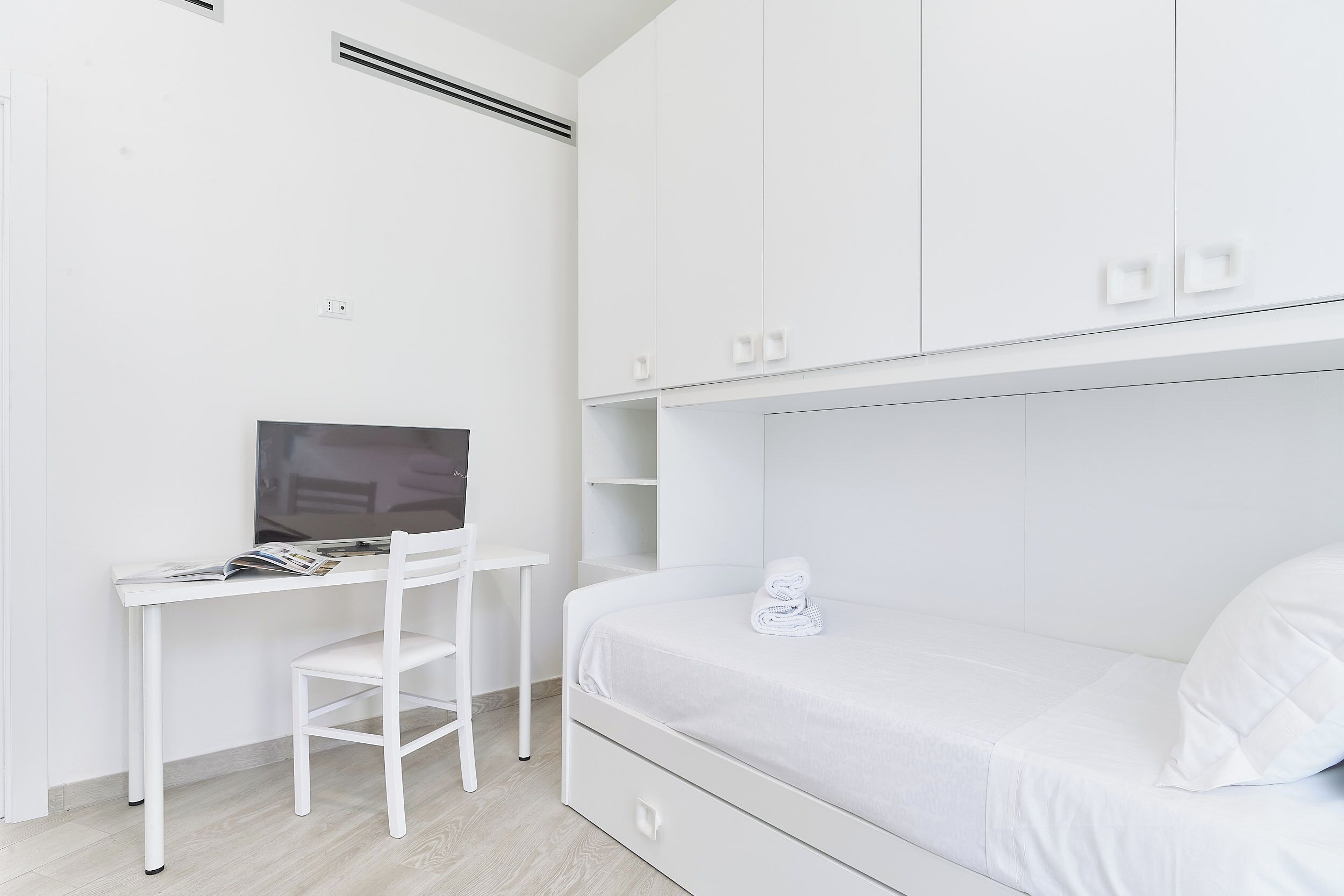 A room with a bed, a desk, and a chair.