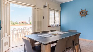 A dining area with a table and chairs, a view through a door, and a wall-mounted ship's wheel. - Villa 'La Conchiglia' with Wi-Fi and Air Conditioning (Licata)