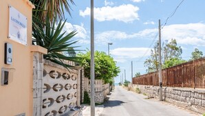 A narrow street with a stone wall on one side and a wooden fence on the other. - Villa 'La Conchiglia' with Wi-Fi and Air Conditioning (Licata)