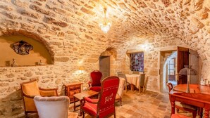 A stone-walled room with a chandelier, wooden furniture, and a red chair. - "Orchidée" Room with Pool, Garden & Provençal Charm in Collias (Collias)