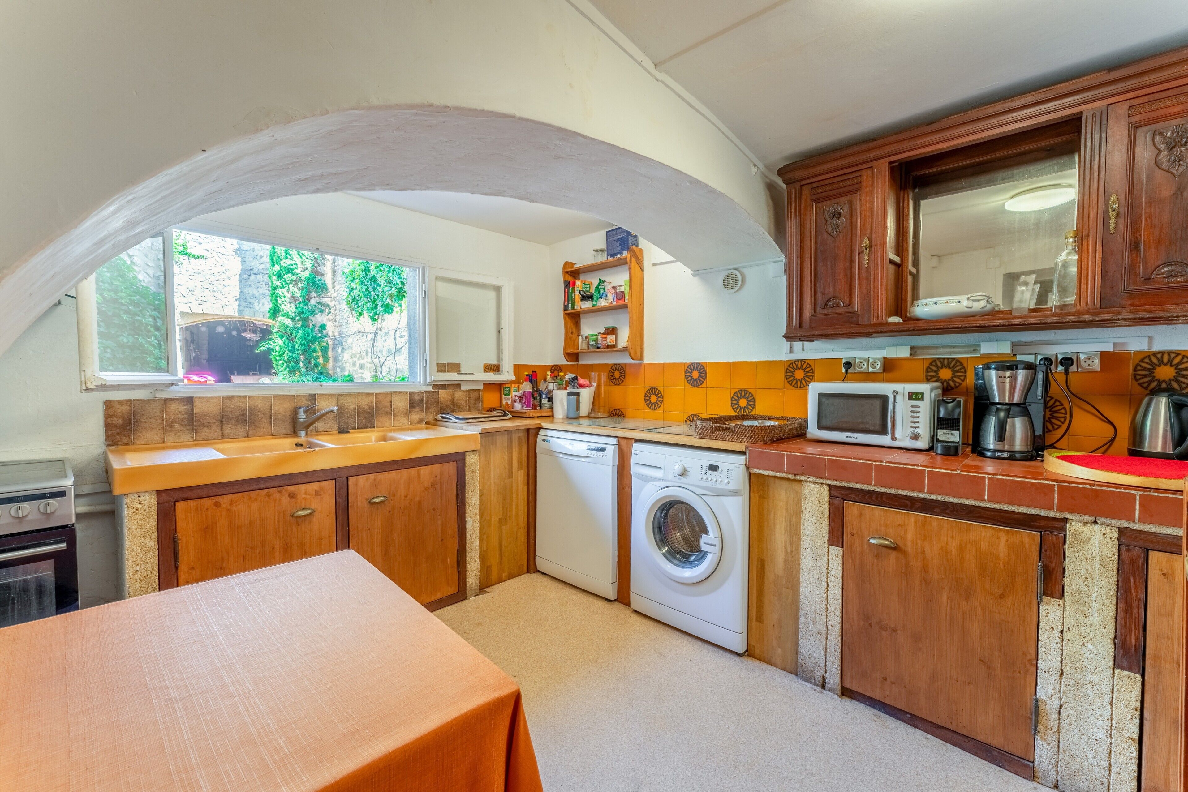 A compact kitchen with wooden cabinets, a washing machine, a microwave, and a sink.