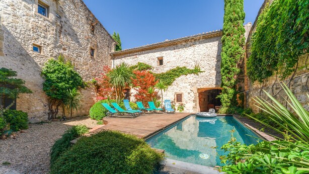 A stone building with a pool, lounge chairs, and greenery. - "Orchidée" Room with Pool, Garden & Provençal Charm in Collias (Collias)