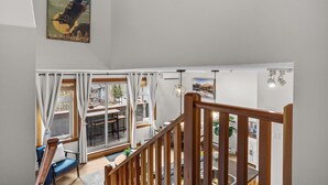 A modern interior with a staircase, a dining area with a view, and a poster on the wall.