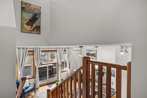 Un intérieur moderne avec un escalier, un coin repas offrant une vue et une affiche accrochée au mur.