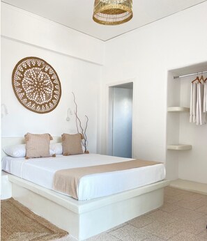 A modern bedroom with a large bed, a wall hanging, and a wardrobe. - CAL DAY ROOMS SANTORINI (Santorini)
