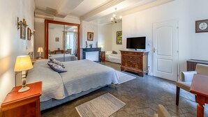 A bedroom with a bed, bedside tables, a dresser, a television, and a door. - Room La Fayette with shared swimming pool, Wi-Fi and air conditioning (Collias)