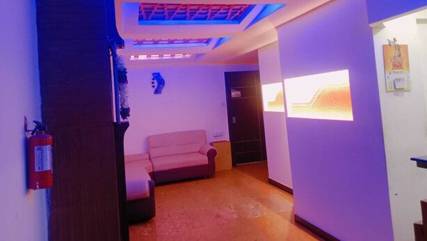 A hallway with a sofa, a fire extinguisher, and a ceiling with a grid pattern.