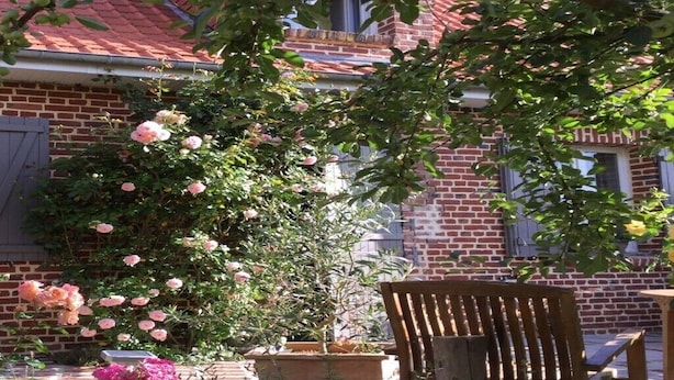 A brick building with a garden area featuring a wooden bench and potted plants.