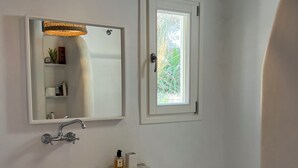 A bathroom with a white sink, a mirror, a window, and a bathtub.