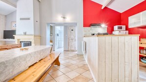 Una cocina con pared roja, una mesa de madera y un banco.