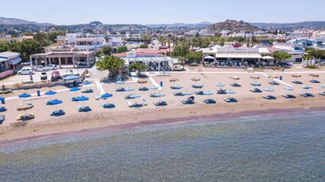 A beachside hotel with multiple lounge areas, a pool, and a view of the surrounding town.