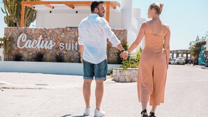 A couple holding hands in front of a sign that reads "Cactus suit." - Cactus Suites  (Faliraki)