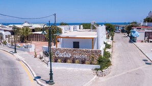 A building with a sign reading "Cactus suites" surrounded by a garden with cacti and other plants. - Cactus Suites  (Faliraki)