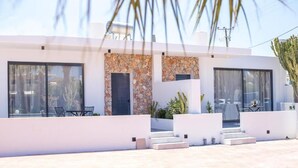A modern building with large windows, a stone facade, and outdoor seating. - Cactus Suites  (Faliraki)