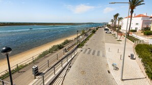 A coastal promenade with a paved walkway, a beach, and a row of buildings. - Casas do Forte AG in Tavira (Tavira)