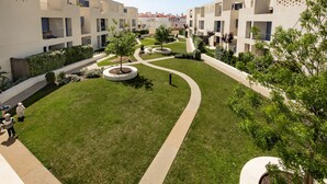 A courtyard with a central pathway, surrounded by multi-story buildings with balconies and a garden area with trees and shrubs. - Casas do Forte AG in Tavira (Tavira)
