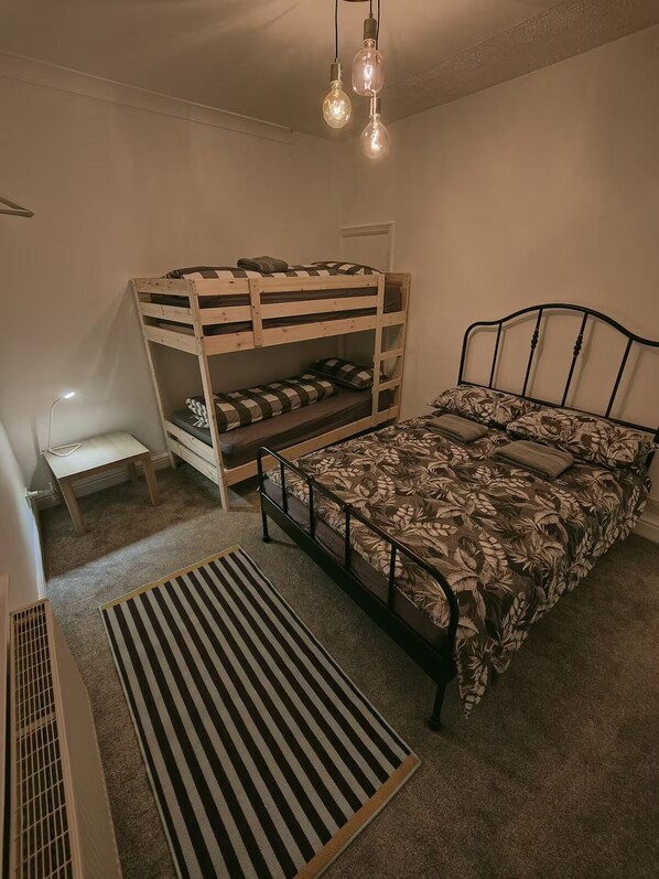 A bunk bed room with a desk, a radiator, and a striped rug.