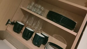 Ein Küchenschrank mit Regalen für Gläser, Teller und Tassen.