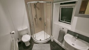 Ein modernes Badezimmer mit einer Duschkabine, einer Toilette, einem Waschbecken und einem Fenster.
