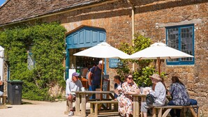 A rustic stone building with a café named "COACH HOUSE" and wooden benches outside. - Countryside Escape on Historic Estate (Mapperton)