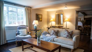A cozy living room with a sofa, armchair, wooden coffee table, and lamps. - Countryside Escape on Historic Estate (Mapperton)
