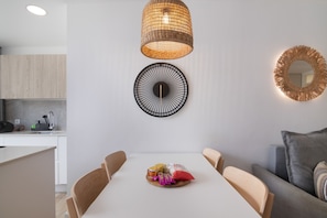 A modern kitchen with white cabinets, a dining table with chairs, and a hanging light fixture. - Vacations at 'Chez Oti' with Shared Pool, Wi-Fi, and Air Conditioning (Puerto Rico de Gran Canaria)