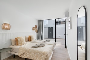 A modern bedroom with two beds, a large mirror, and a view of the outside. - Vacations at 'Chez Oti' with Shared Pool, Wi-Fi, and Air Conditioning (Puerto Rico de Gran Canaria)