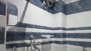 A small bathroom with a pedestal sink, a toilet, and a shower. - Hotel Shiv Ganga (Varanasi)