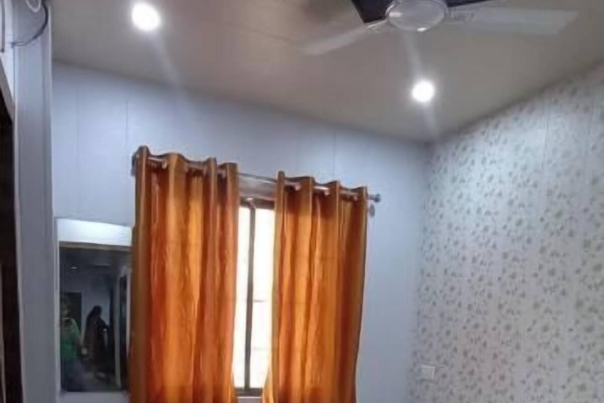 Un dormitorio con cama, cortinas, ventilador de techo y suelo de baldosas.