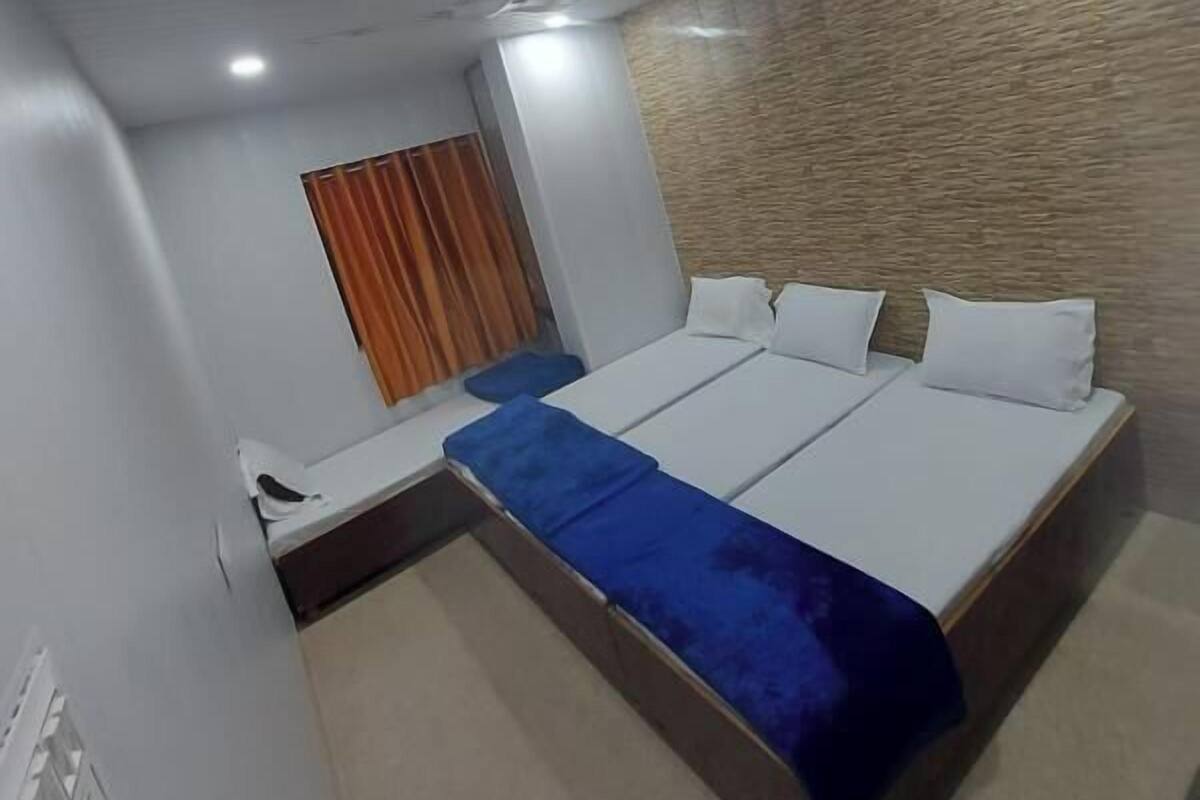 Una habitación de hotel con una cama, una mesita, un ventilador de techo y un equipo de aire acondicionado.