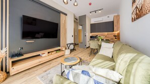 Un soggiorno moderno con televisore piatto, mobile TV in legno, divano verde e un tavolino rotondo.
