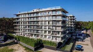 Un edificio residenziale a più piani con balconi, un giardino curato e un’area di parcheggio.