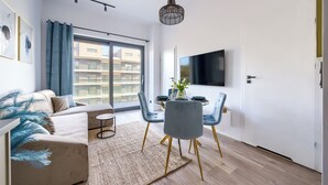 Un soggiorno moderno con divano, tavolo da pranzo, sedie e televisore a parete.