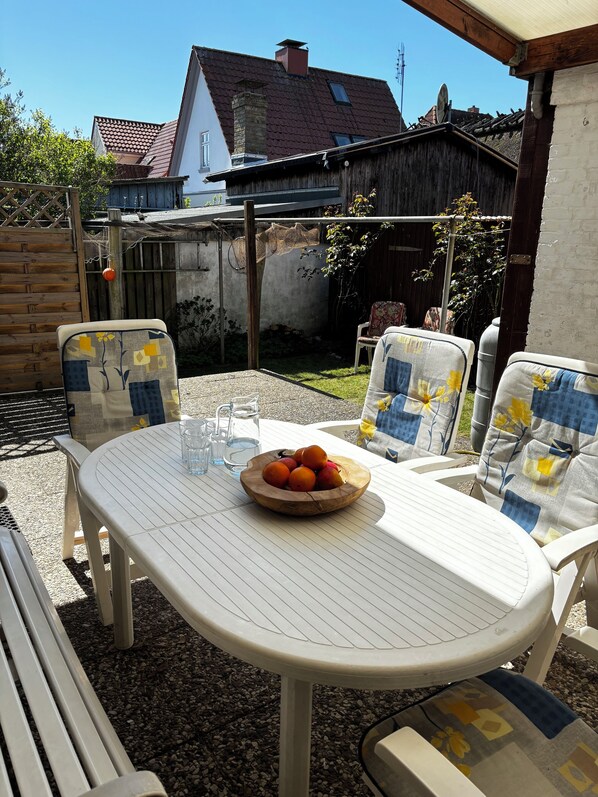 Un patio con una mesa redonda, dos sillas y un frutero.