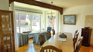A dining area with a wooden table, chairs, a chandelier, and a view of the outside. - Vacation apartment no. 2 with its own jetty/barge (Maasholm)