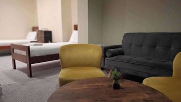 A hotel room with a bed, a sofa, a round wooden table, and a small plant.