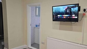 Un televisor montado en una pared en un pasillo con una puerta que da a un baño.