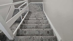Una escalera con alfombra estampada y barandillas blancas.