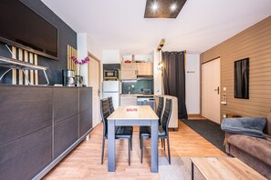 Et moderne køkken med spiseplads, træskabe og et fladskærms-tv.
