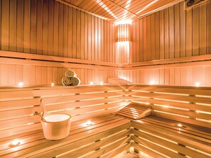 Eine Sauna mit Holzbänken, einem Eimer und einem Stapel Handtüchern.