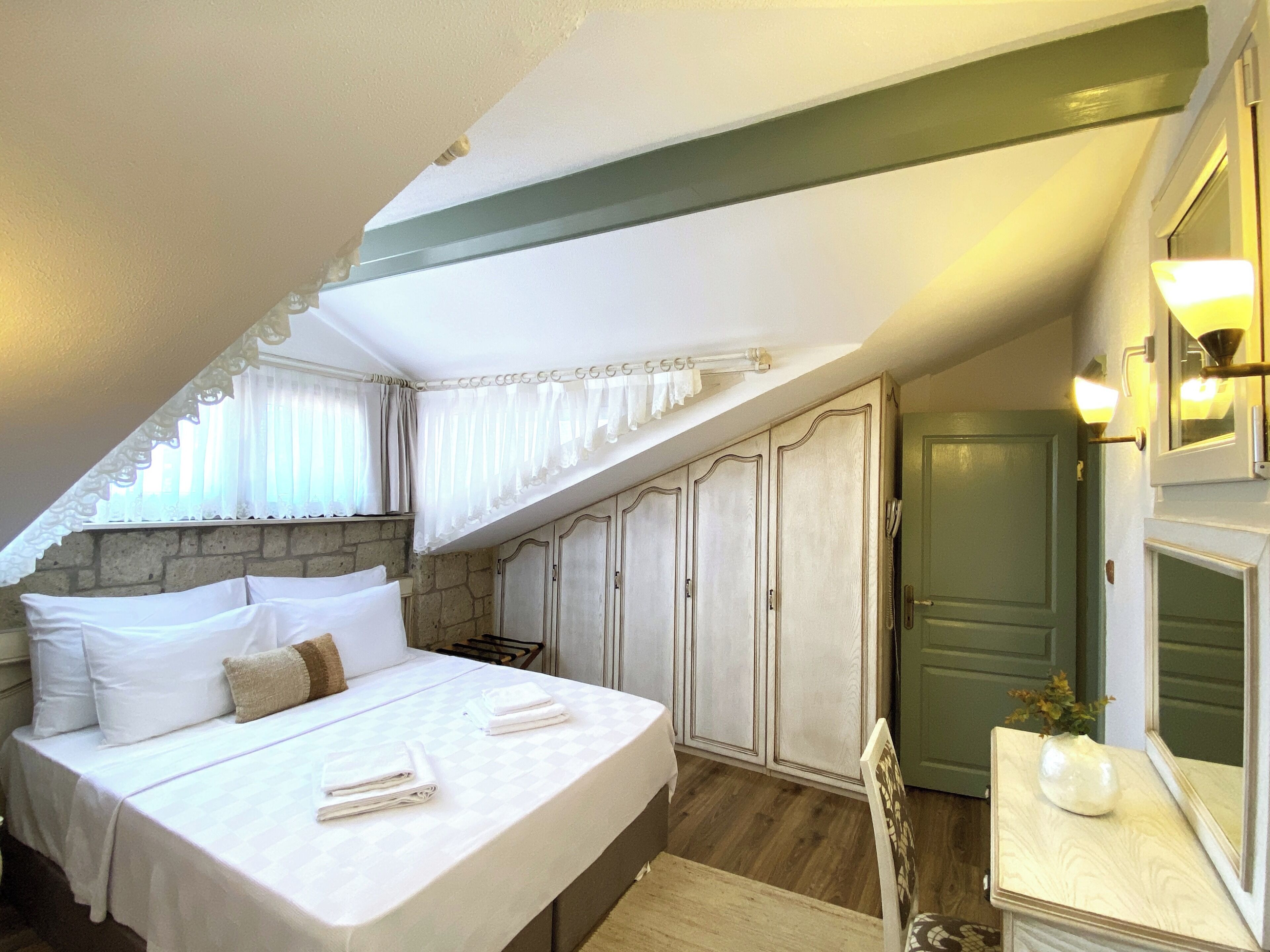 Een slaapkamer met een bed, een dressoir, een spiegel en een deur.