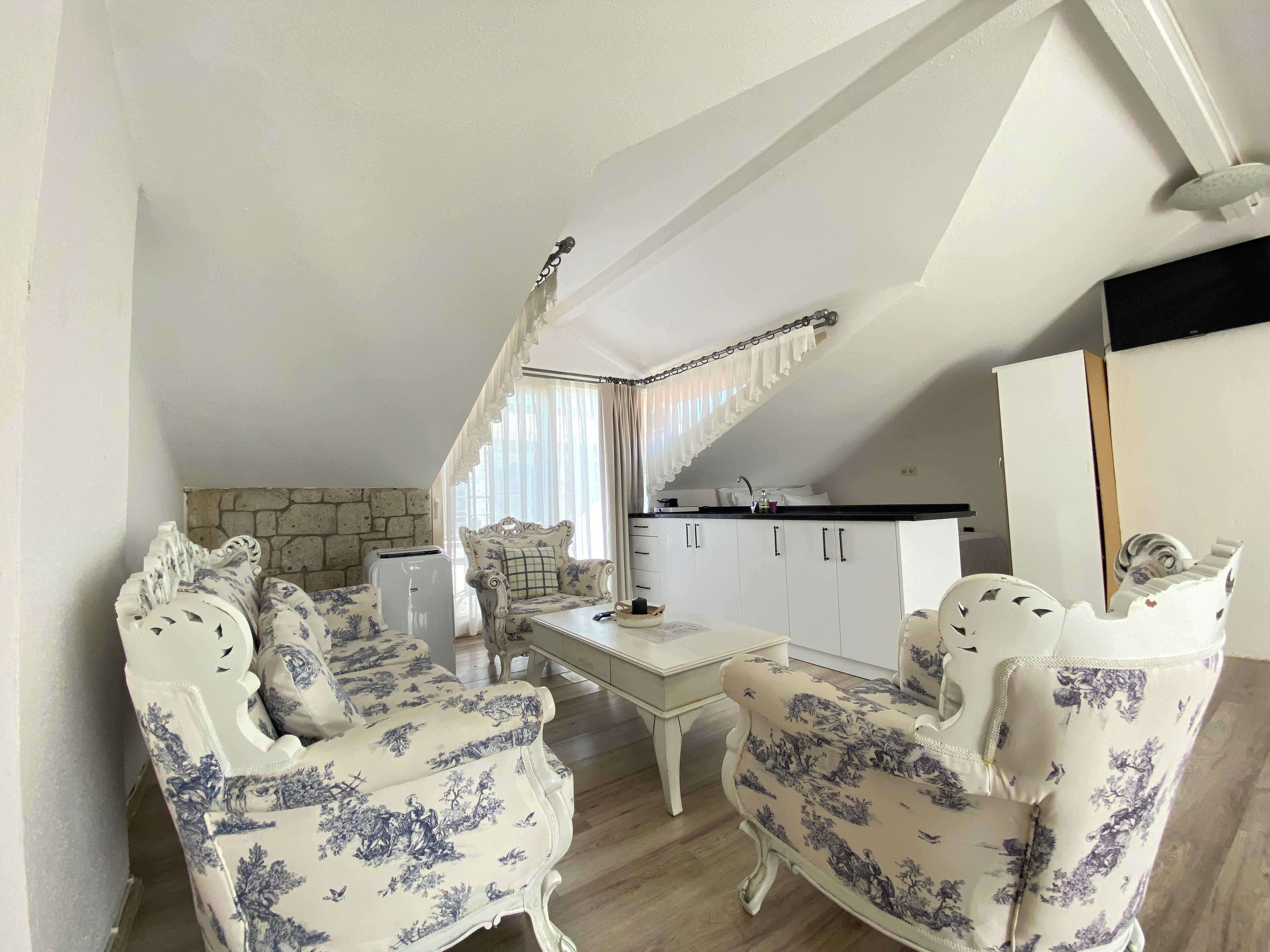 Un salón acogedor con dos sillones decorados, una mesita y un armario blanco al fondo.