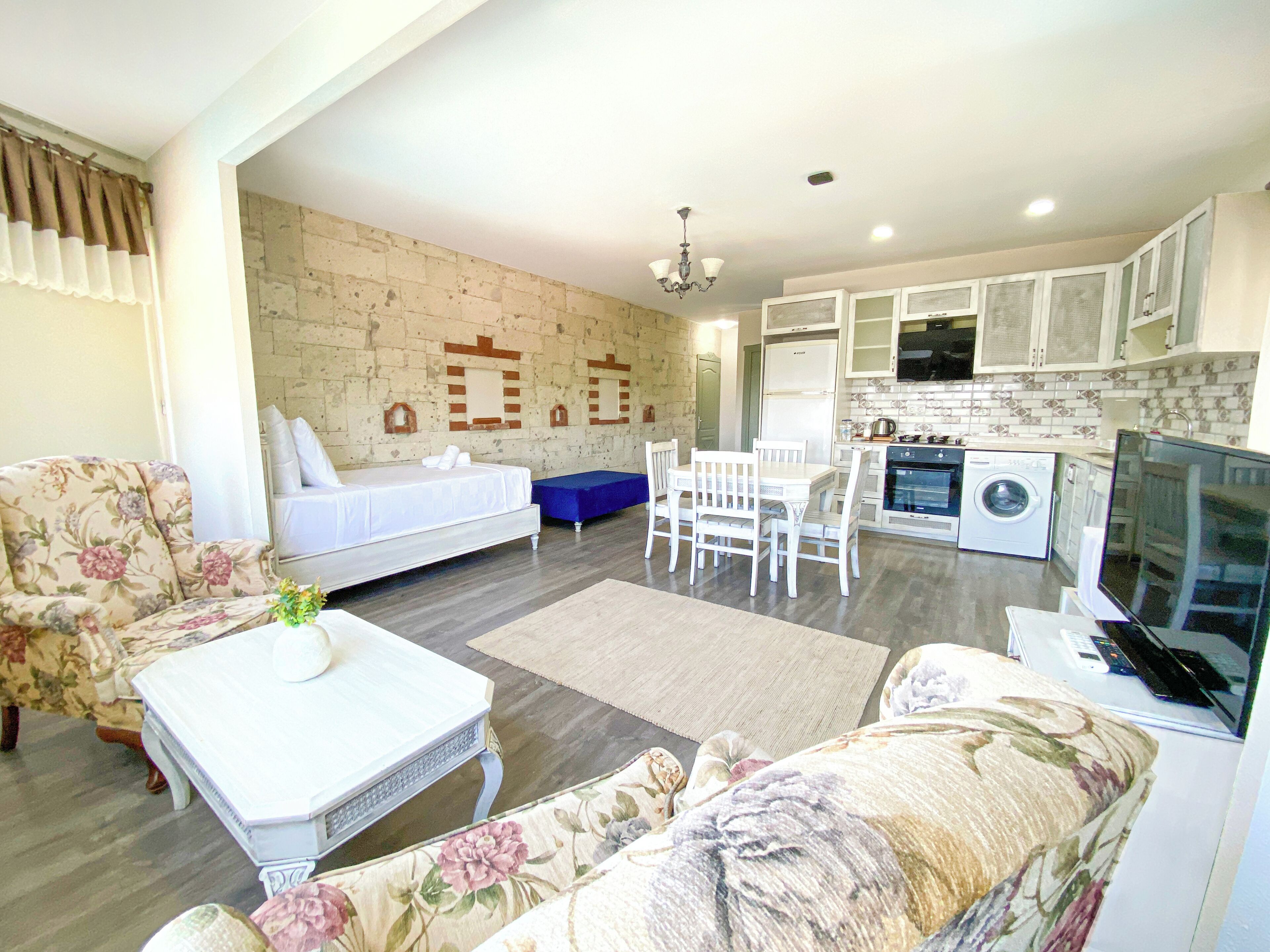 A compact living space with a bed, sofa, dining table, and kitchenette.