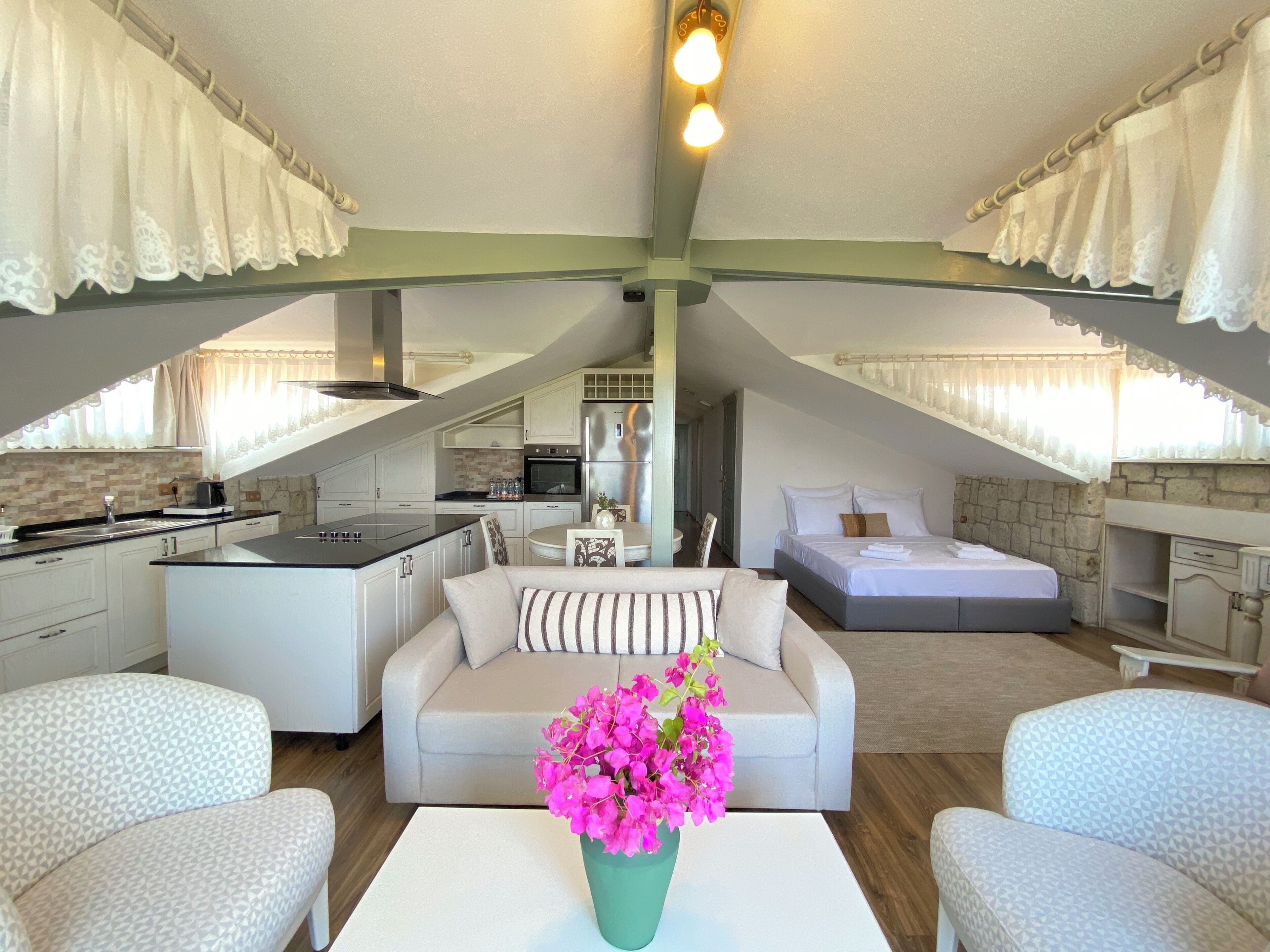 A modern loft bedroom with a large bed, a sofa, and a dining area.