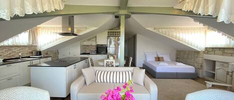 A modern loft bedroom with a large bed, a sofa, and a dining area.