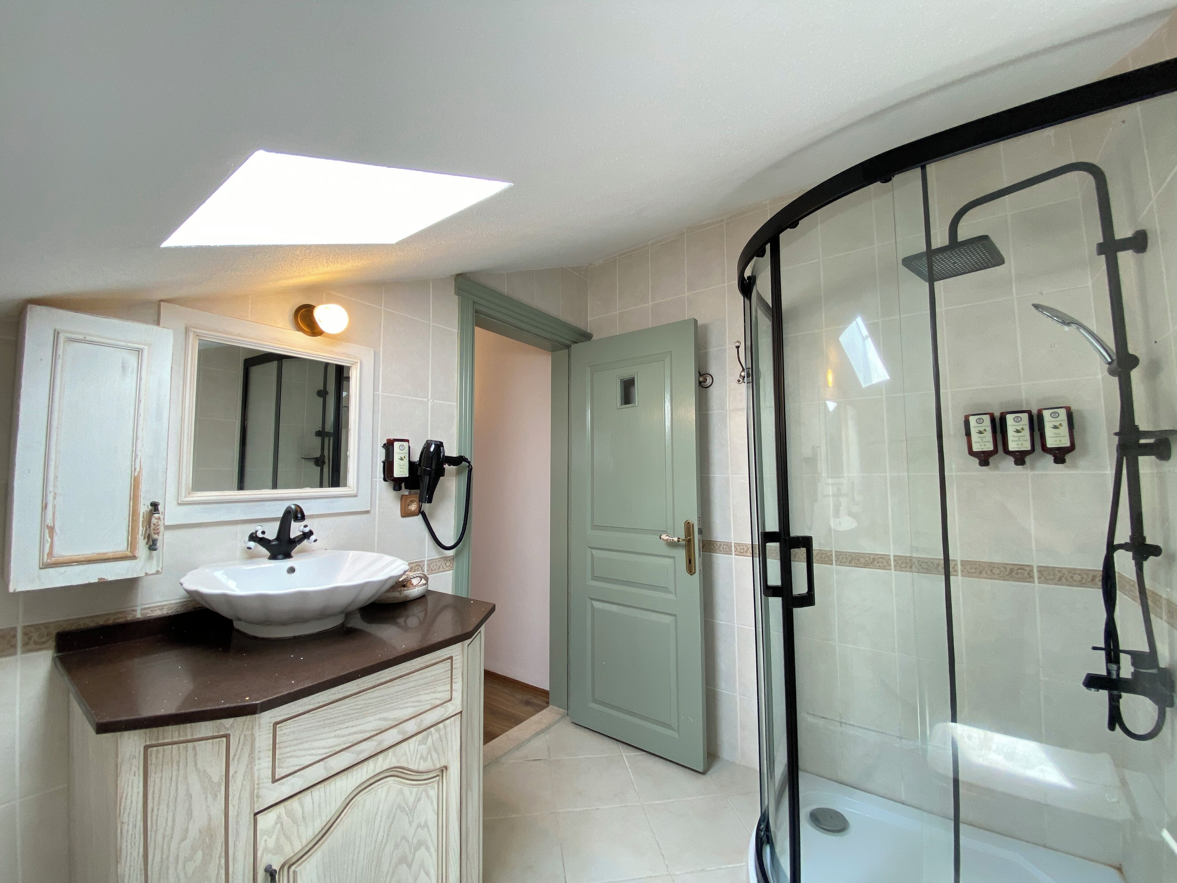 A bathroom with a sink, mirror, and shower.