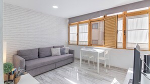 Una habitación moderna con un sofá gris, una mesa blanca y un televisor.