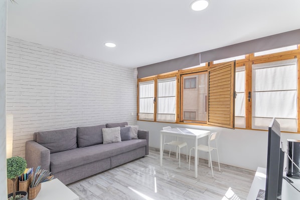 A modern room with a grey sofa, a white table, and a TV.