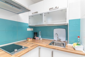 A modern kitchen with a wooden countertop, stainless steel sink, and a built-in induction cooktop.