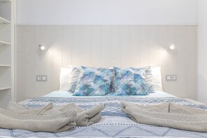 A bed with patterned bedding, two pillows, and two folded towels.